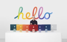 This handout released and taken on April 20, 2021 by Apple inc. shows Apple CEO Tim Cook posing next to the redesigned iMac featuring the company's new in-house M1 chip .