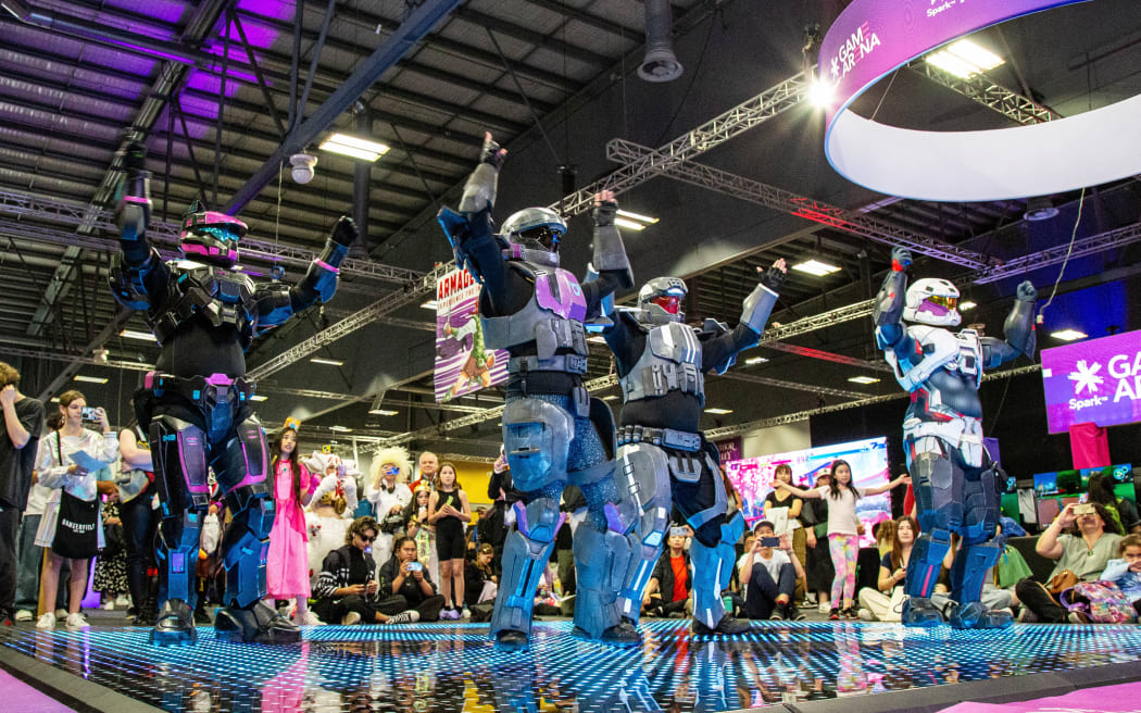 People dressed in elaborate costumes dance on stage at Armageddon expo.