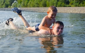 A father and his young son swim in a river (file)