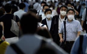 People wearing face masks walk during the evening rush hour from Shinagawa railway station in Tokyo on June 24, 2020.