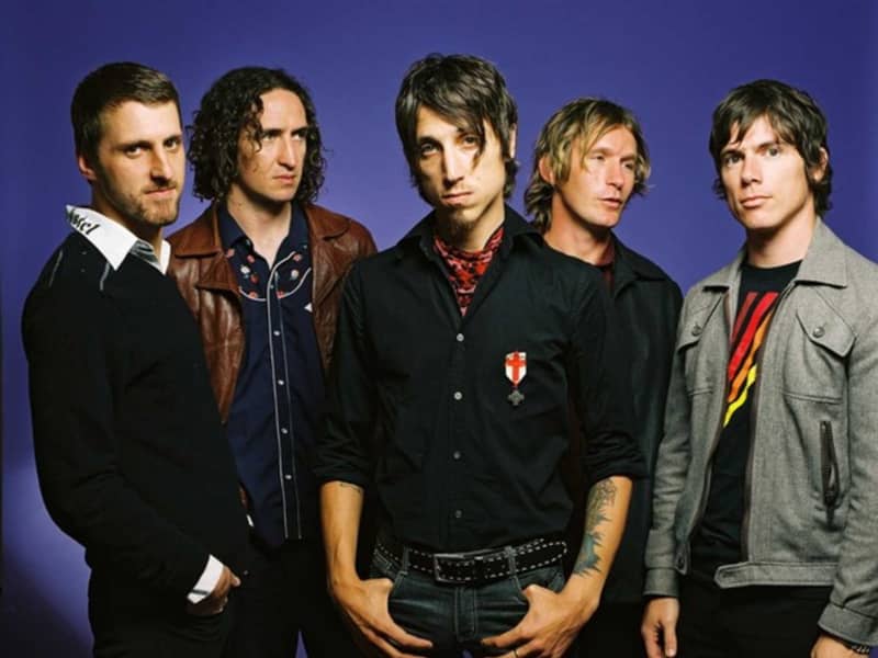 Five men stand in a line looking tough.