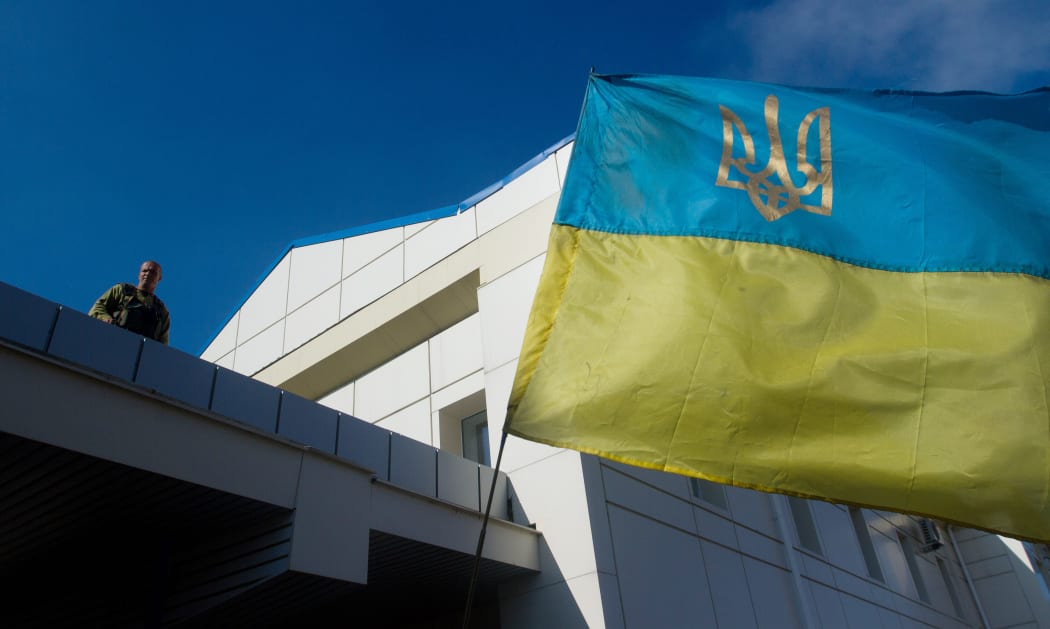 A serviceman of the pro-Ukrainian Aydar battalion stands near the Ukrainian flag at the Lugansk thermoelectric power station.