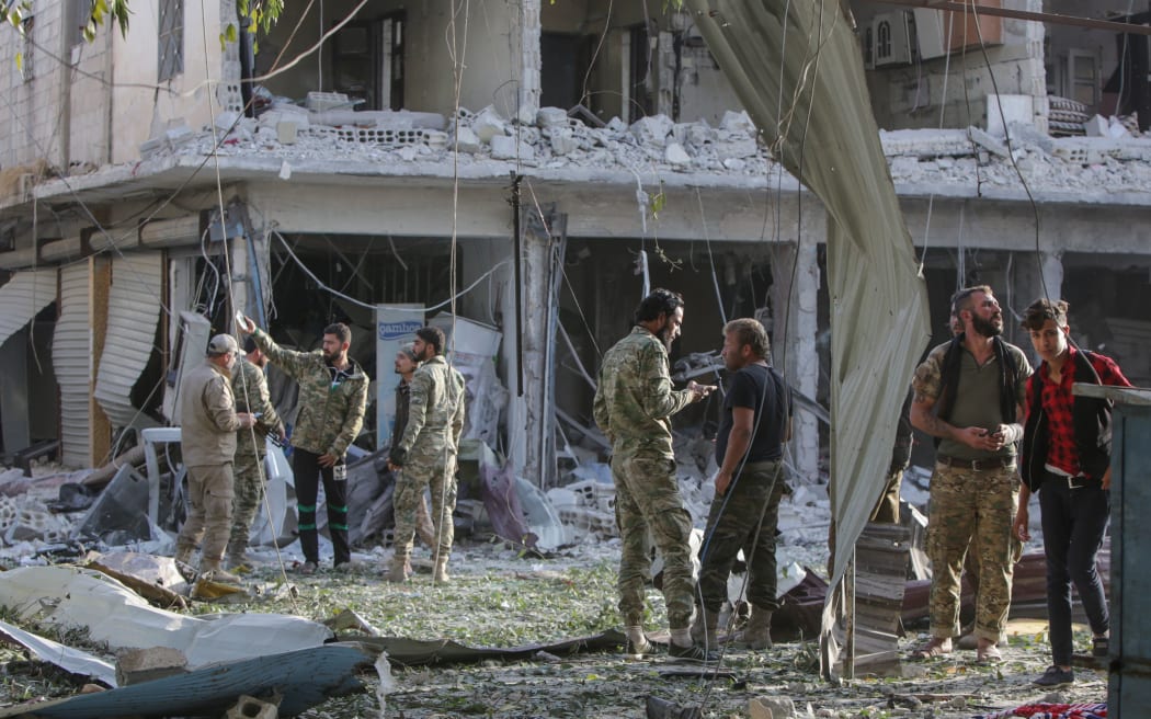 Turkey-backed Syrian fighters inspect the site of a car bomb explosion in the northern Syrian Kurdish town of Tal Abyad, on the border with Turkey, on November 2, 2019.