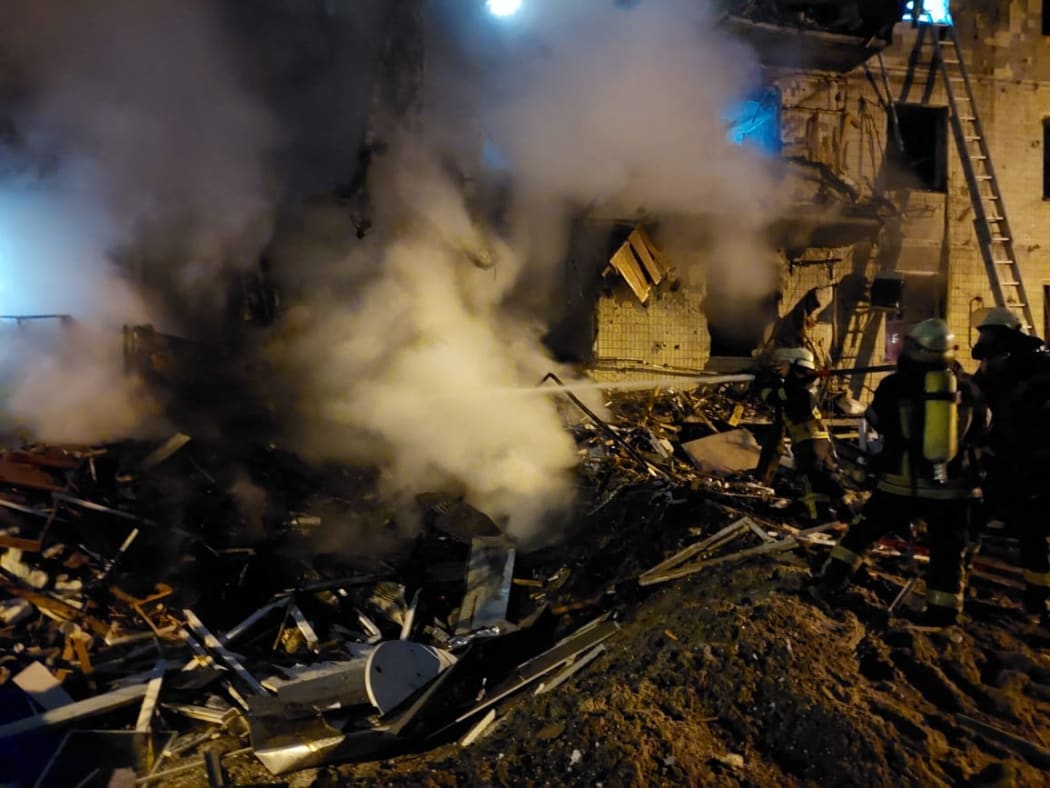 Firefighters extinguish a blaze at a damaged residential building at Koshytsa Street in the Ukrainian capital Kyiv, early on 25 February 2022.
