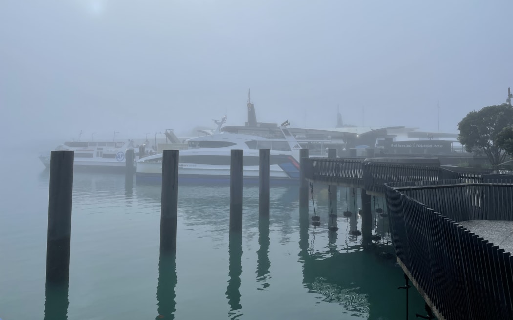 Ferries are barely visible in Auckland's harbour as fog blankets the city on 16 July 2024.