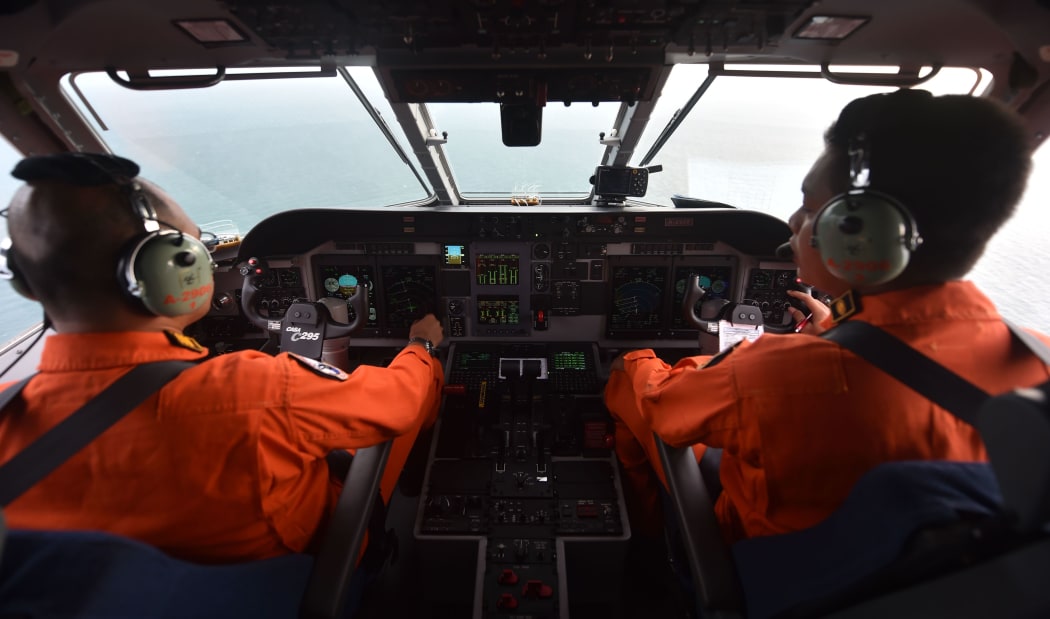 A pilot and co-pilot in the Indonesian air force keep a look out during search and rescue operations for the missing AirAsia flight QZ8501.