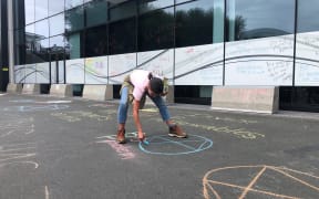 A protestor, Danielle Jones, makes her mark on the concrete outside BP’s Auckland office.