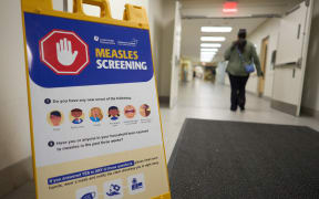 A person walks past a measles screening sign near an entrance at Victoria Hospital in London, Ontario on 9 July, 2025.