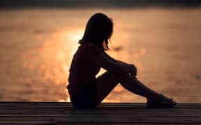 Sad woman silhouette worried at sunset