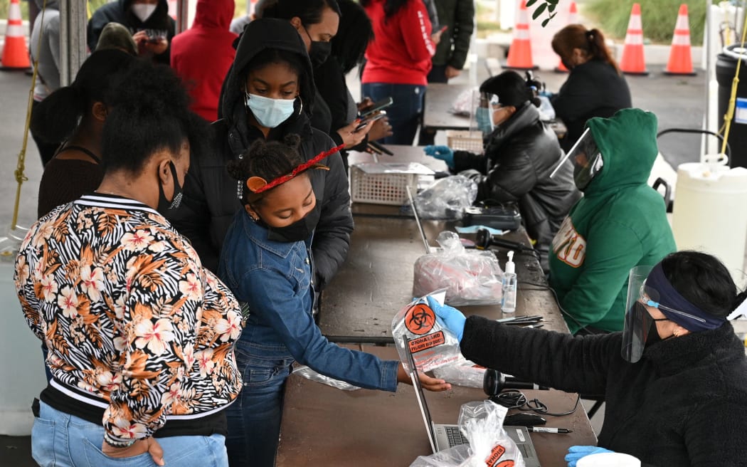 A young girl receives a self-administered Covid-19 test kit at a screening center at the Martin Luther King, Jr. (MLK) Medical Center Campus in South Los Angeles, California, on December 27, 2021,