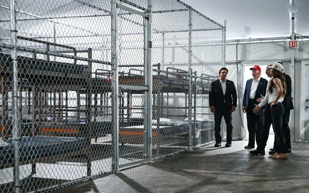 US President President Donald Trump (2L), Florida Governor Ron DeSantis (L), and Secretary of Homeland Security Kristi Noem (R) tour a migrant detention center, dubbed "Alligator Alcatraz," located at the site of the Dade-Collier Training and Transition Airport in Ochopee, Florida on July 1, 2025. President Trump is visiting a migrant detention center in a reptile-infested Florida swamp dubbed "Alligator Alcatraz." Trump will attend the opening of the 5,000-bed facility -- located at an abandoned airfield in the Everglades wetlands -- part of his expansion of deportations of undocumented migrants, his spokeswoman said. (Photo by ANDREW CABALLERO-REYNOLDS / AFP)