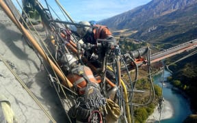 Workers and gear hanging off the side of a cliff.
