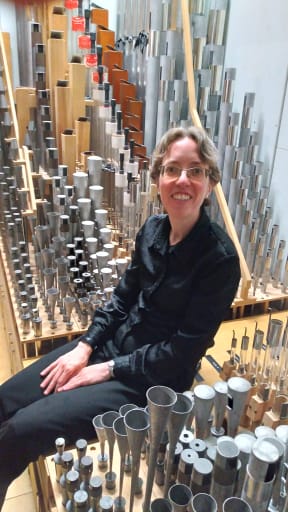 Isabelle Demers sitting amongst some of the pipes of the Auckland Town Hall Organ