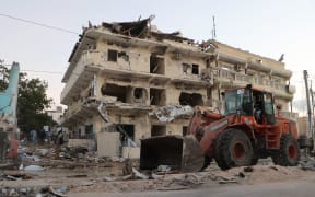 A backhoe loader clean the street outside the Maka Al-Mukarama hotel in the Somalia capita