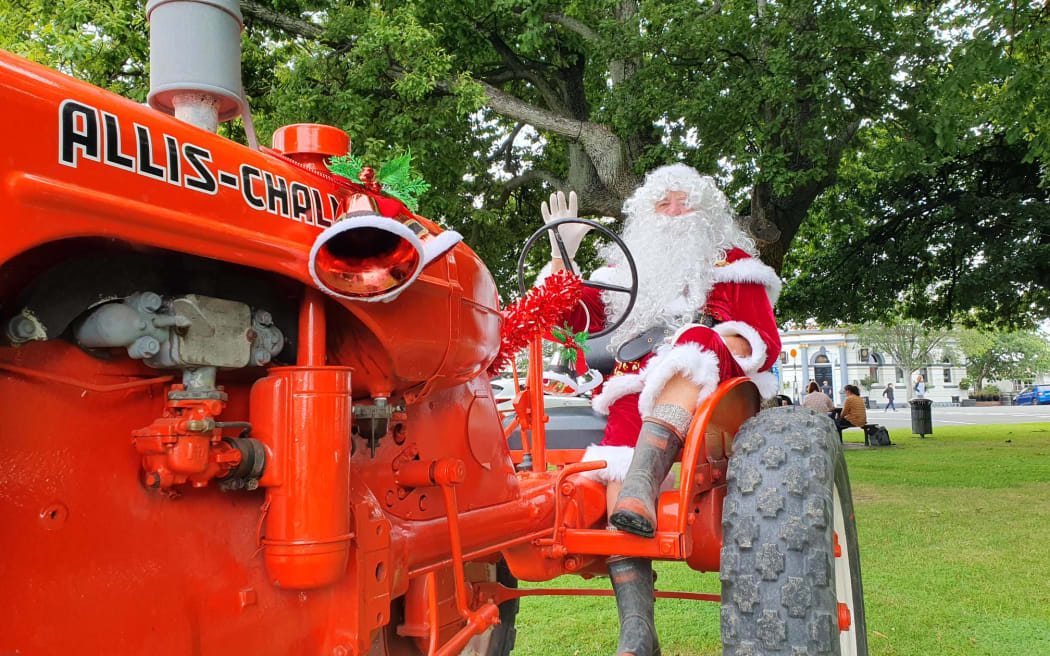 Santa waves hello on his big red tractor.