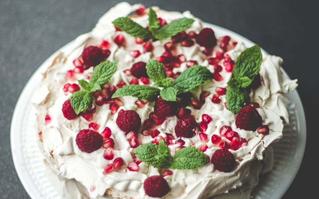 A pavlova with berries and mint.