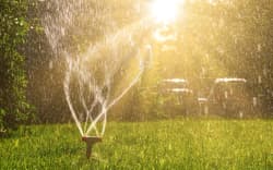 Lawn sprinkler with a lot of copy-space and sun shining from back side