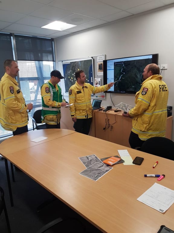 Fire and Emergency New Zealand crew discusses the plan for managing the Skippers Canyon fire today.