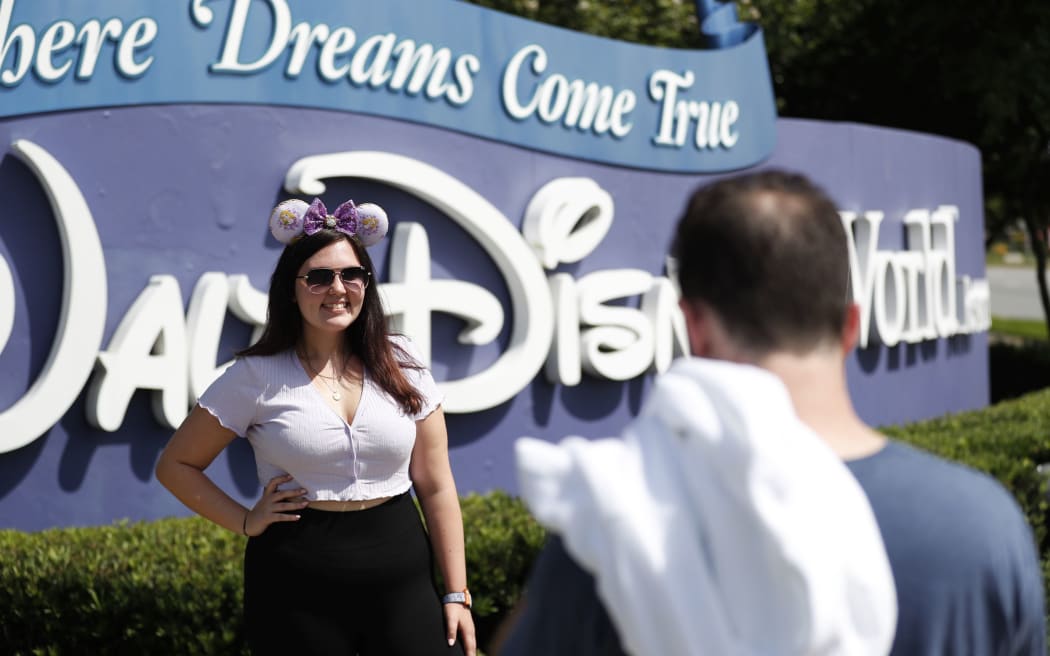 LAKE BUENA VISTA, FL - JULY 09: Michael Callahan (R) takes a photo of his friend Sarah Breland near the Walt Disney World theme park entrance World on July 9, 2020 in Lake Buena Vista, Florida.