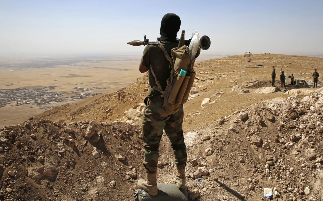 A Kurdish Peshmerga fighter overlooking a village near Mosul controlled by Islamic State.