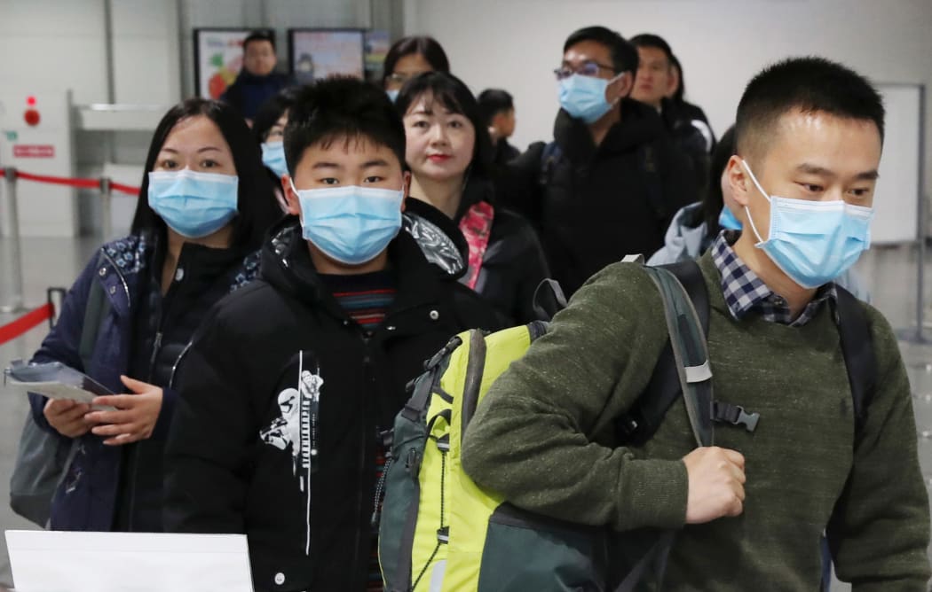 Passengers wearing mask walk at quarantine inspection during the time when a flight arrived from Wuhan at Kansai International Airport in Osaka.