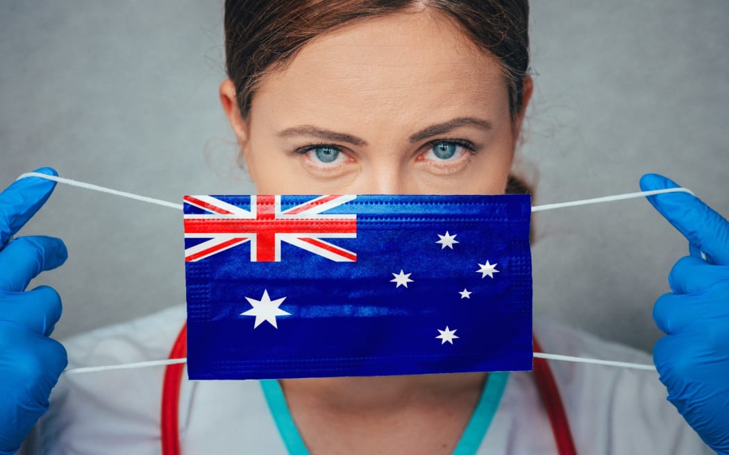 Coronavirus in Australia Female Doctor Portrait hold protect Face surgical medical mask with Australia National Flag. Illness, Virus Covid-19 in Australia, concept photo