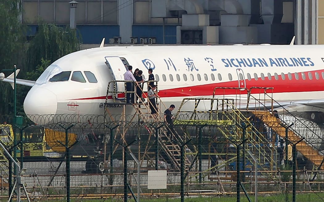 Employees checking the plane after its cockpit window broke (pictured).