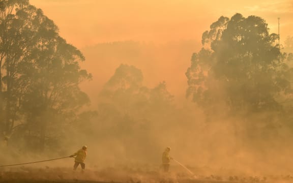 Firefighters defend a property from a bushfire at Hillville near Taree, 350km north of Sydney, on 12 November, 2019.
