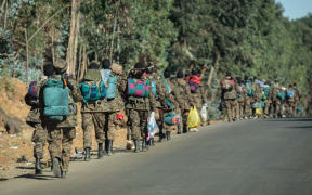 Soldiers of the Ethiopian National Defense Force (ENDF) walk along a road toward the frontline in Gashena.