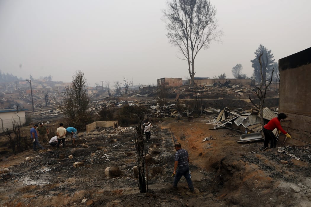 People work to clean up the debris after a forest fire devastated Santa Olga, 240 kilometres south of Santiago