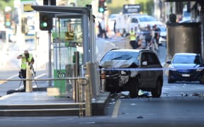 A white SUV sits in the middle of the secen after being driven into pedestrians