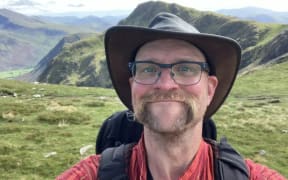 Jonas Skogscroll with a pack on his back and hills in the background