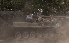 Ukrainian servicemen sit on a self-propelled artillery 2S7 Pion while being carried by a military truck, in the Sumy region, near the border with Russia, on August 11, 2024, amid the Russian invasion of Ukraine. (Photo by Roman PILIPEY / AFP)