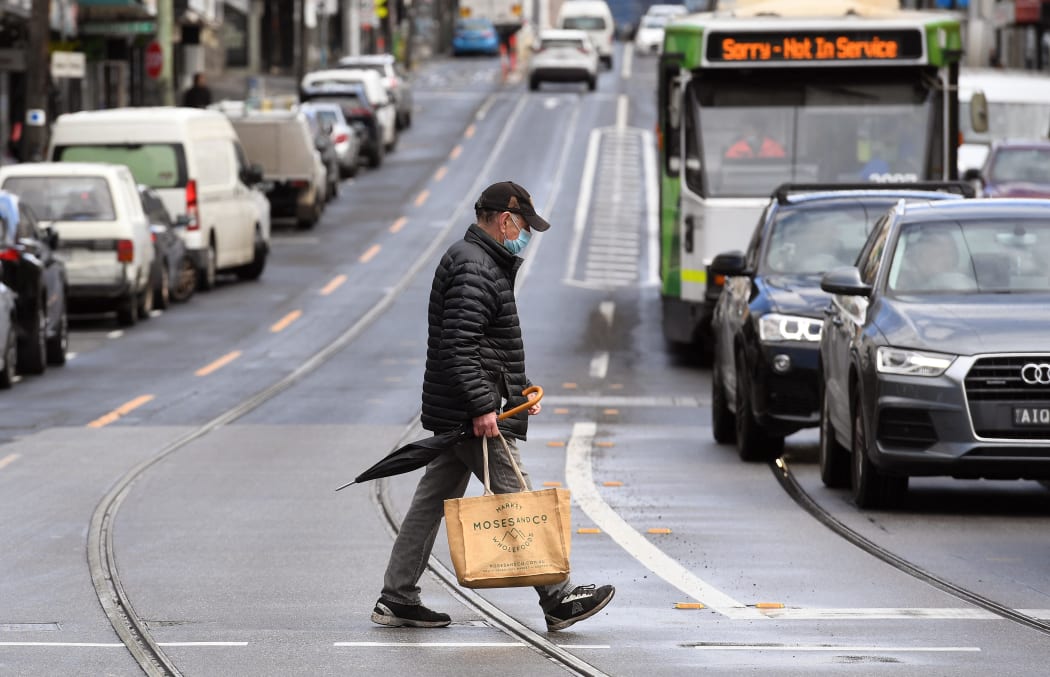 A man crosses a street in Melbourne on October 11, 2021, during a lockdown against Covid-19 coronavirus as Sydney ended a 106-day lockdown.
