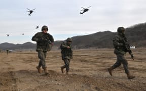 South Korean soldiers move to a position as US Army UH-60 Black Hawk helicopters fly overhead during a joint South Korea-US drill at a military training field in the border city of Paju on 16 March, 2023, as part of the Freedom Shield joint military exercise.