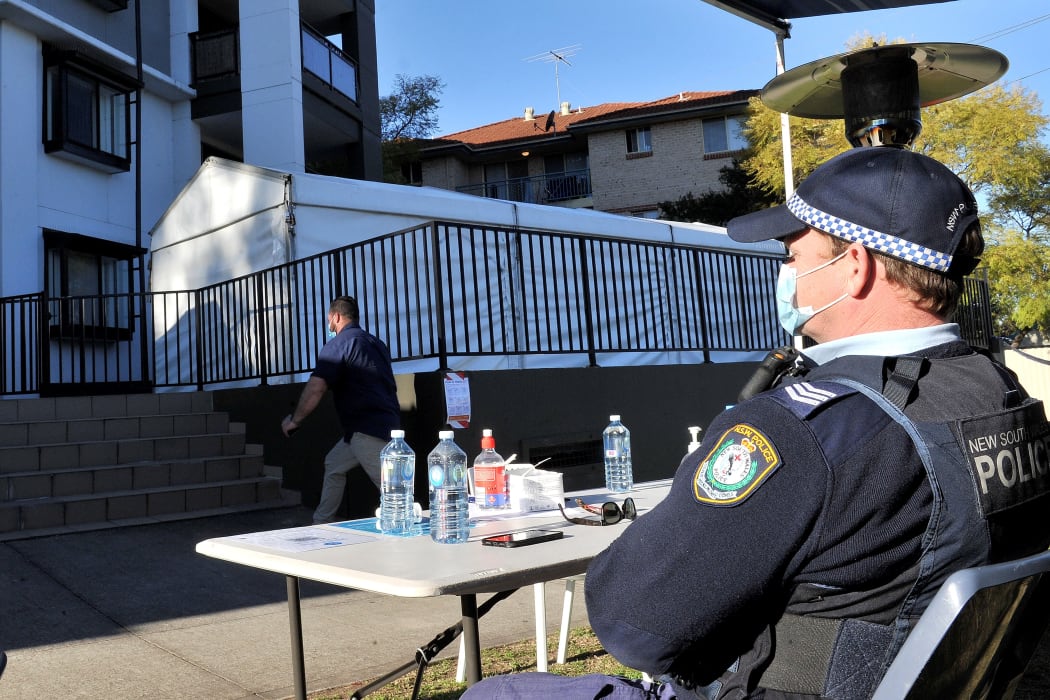 A police officer stays guard outside an isolated residential building in Sydney's western suburb of Blacktown after several cases were reported among the residents.