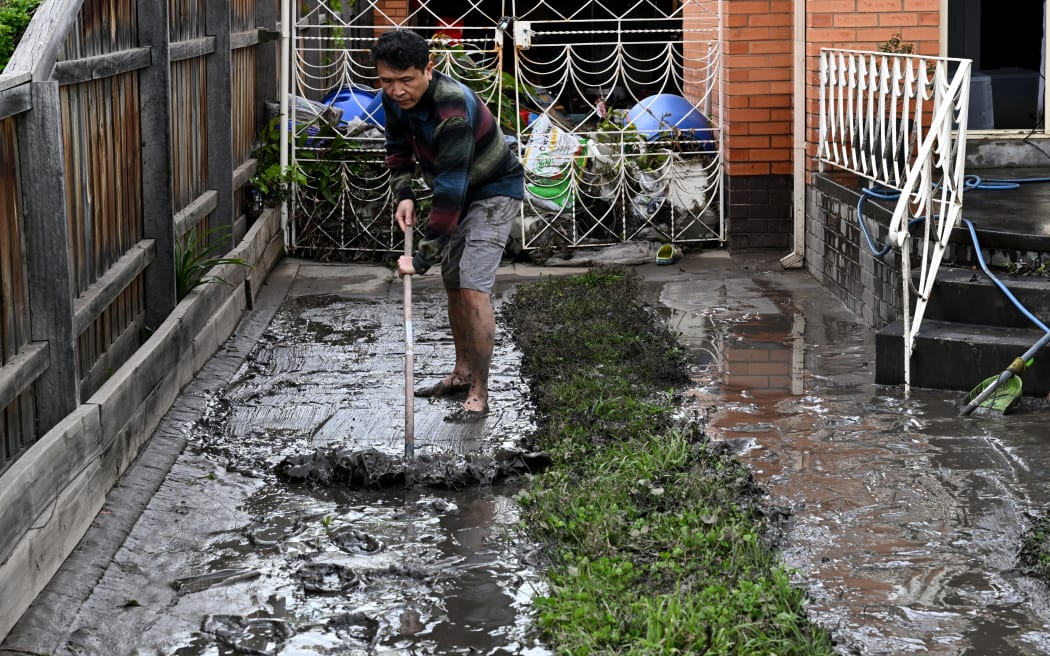 A man clears mud from a property affected by floods in the Melbourne suburb of Maribyrnong on October 15, 2022. - Australia reported the first fatality from days of widespread flash flooding on October 15, 2022 despite heavy rains easing and flood levels topping out across much of the southeast. Hundreds of homeowners began a long clean-up after storm waters engulfed streets, houses and cars across three states, with Melbourne suburbs among the worst hit. (Photo by William WEST / AFP)