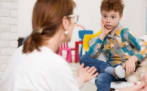 Stock image representing school psychologist talking to young boy.