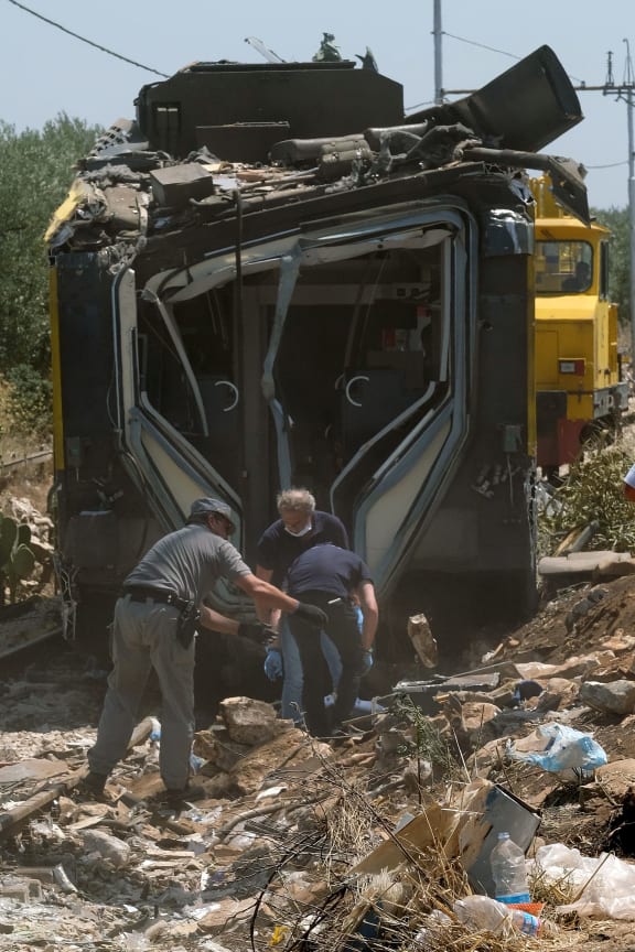 Members of the Italian Dental Division inspect the train crash site on July 13, 2016 near Corato, in the southern Italian region of Puglia as rescuers searched for missing bodies