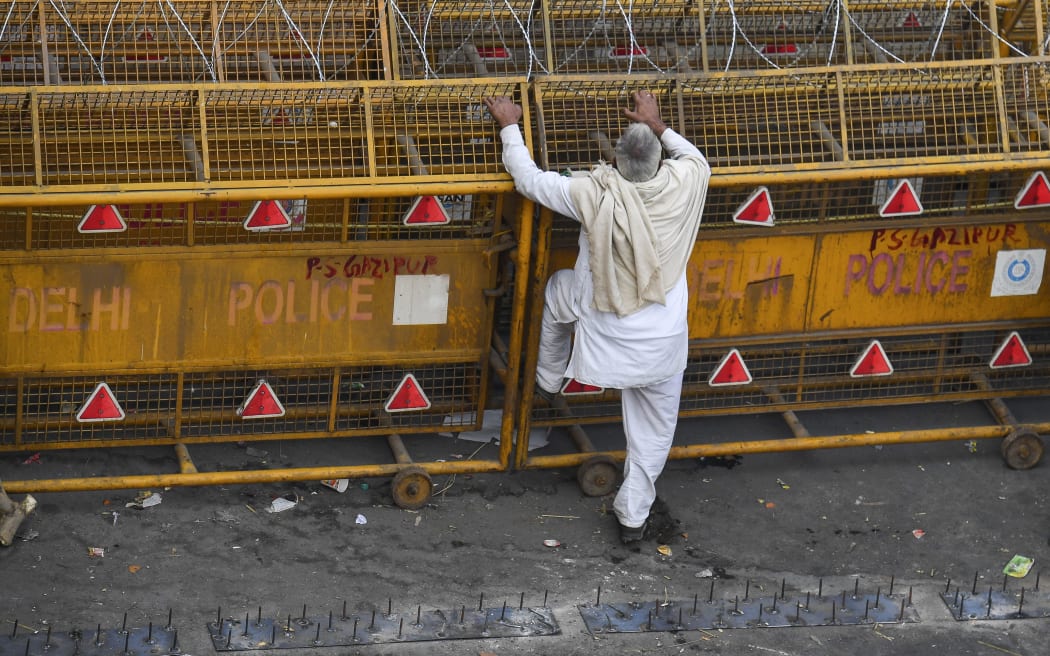 A farmer stands next to police barricades along a blocked highway as farmers continue to protest against the central government's recent agricultural reforms at Delhi-Uttar Pradesh state border in Ghaziabad on 2 February 2021.