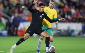 Marko Stamenic of New Zealand competes for the ball with Jackson Irvine of Australia.