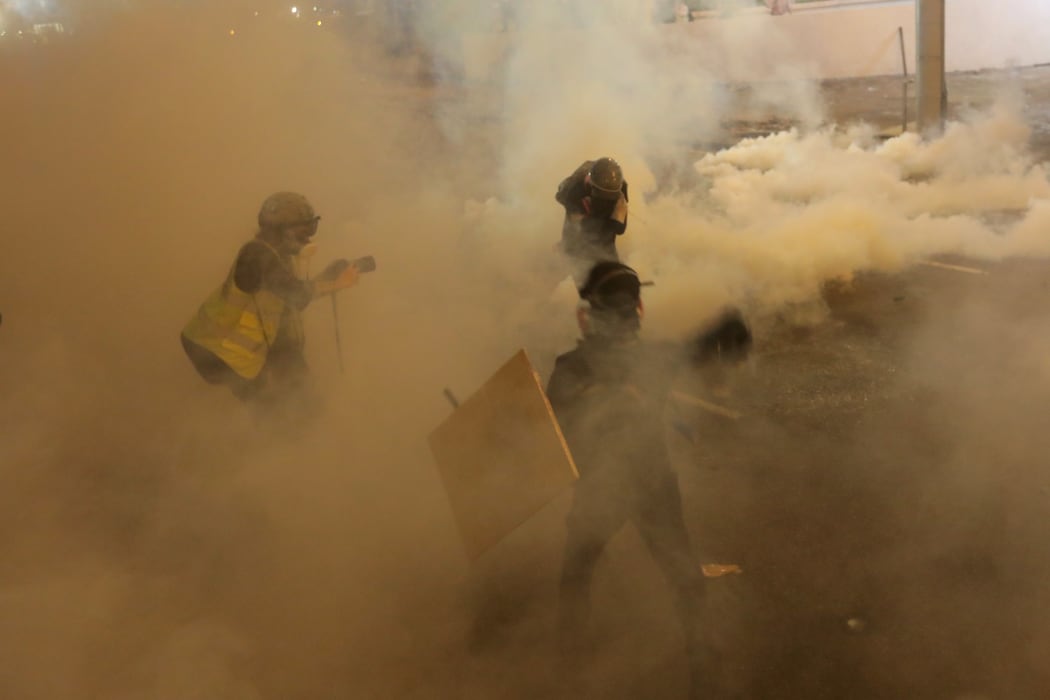 Protesters run from tear gas fired by police after a march against a controversial extradition bill in Hong Kong on July 21, 2019