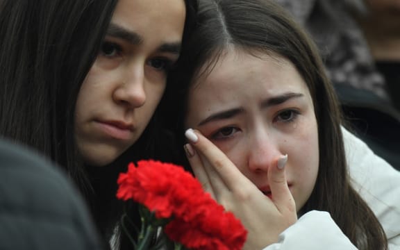 People mourn at a makeshift memorial in front of the Crocus City Hall, a day after a gun attack in Krasnogorsk, outside Moscow, on March 23, 2024. Camouflaged assailants opened fire at the packed Crocus City Hall in Moscow's northern suburb of Krasnogorsk on March 22, 2024, evening ahead of a concert by Soviet-era rock band Piknik in the deadliest attack in Russia for at least a decade. Russia on March 23, 2024, said it had arrested 11 people - including four gunmen - over the attack on a Moscow concert hall claimed by Islamic State, as the death toll rose to over 100 people. (Photo by Olga MALTSEVA / AFP)