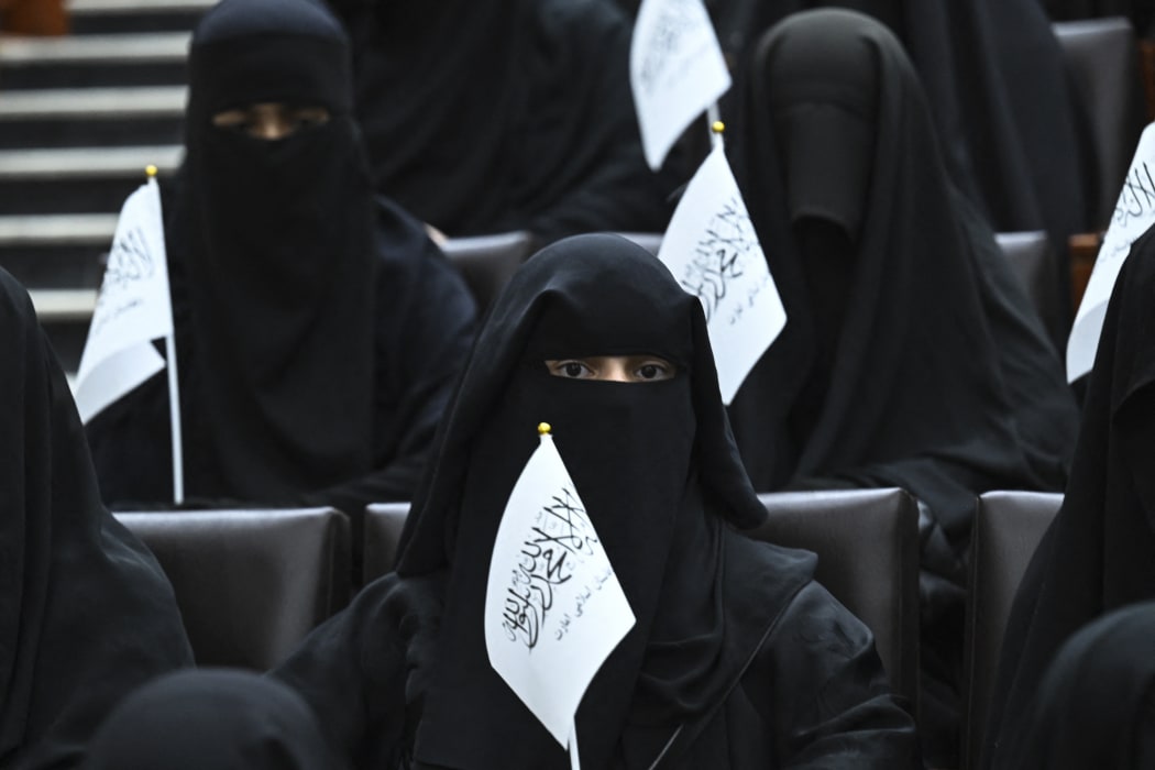 Veiled students hold Taliban flags as they listen to a speaker before a pro-Taliban rally at the Shaheed Rabbani Education University in Kabul on 11 September 2021.