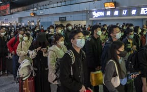 Passengers wearing face masks waiting at a ticket gates to board a high speed railway train in Guangzhou South railway station on January 15, 2023 in Guangzhou, China. China is currently experiencing Spring Festival travel season where millions of Chinese travel around the country before the celebration of the Chinese or Lunar New Year. (Photo by Vernon Yuen/NurPhoto) (Photo by Vernon Yuen / NurPhoto / NurPhoto via AFP)