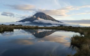 Mt Taranaki is reflected in a tarn on the Pouakai Crossing.