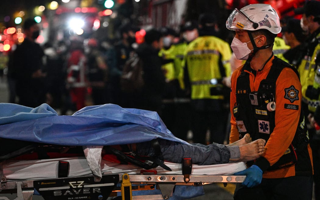 A victim of a Halloween crush, which left at least 120 people dead, is transported on a stretcher in the district of Itaewon in Seoul on October 30, 2022. - At least 120 people were killed on October 29 and some 100 were injured in a stampede in central Seoul when thousands crowded into narrow streets to celebrate Halloween, officials said. (Photo by Anthony WALLACE / AFP)