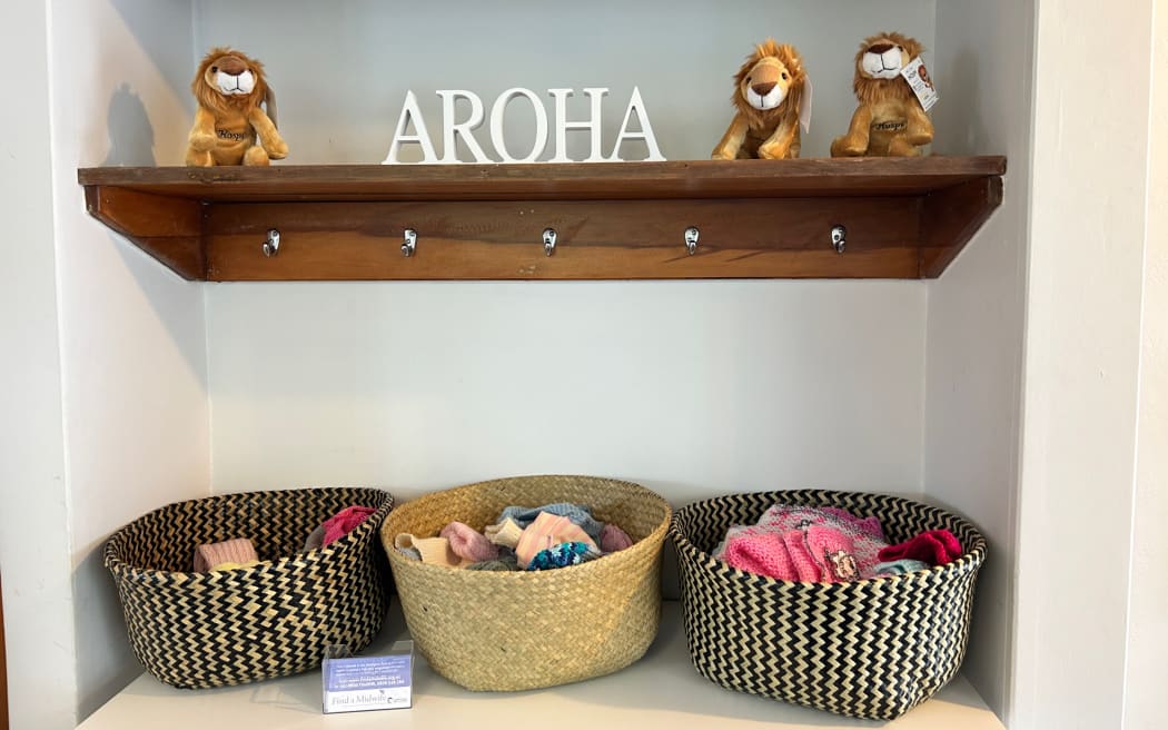 A wall display at the centre with baskets, stuffed toys and aroha written in white letters.