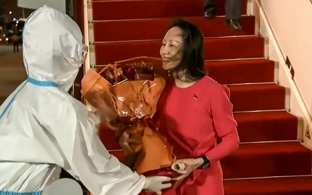 This screen grab made from video released on September 25, 2021 by Chinese state broadcaster CCTV shows Huawei executive Meng Wanzhou receiving flowers after she arrived following her release, in Shenzhen in China's southern Guangdong province.