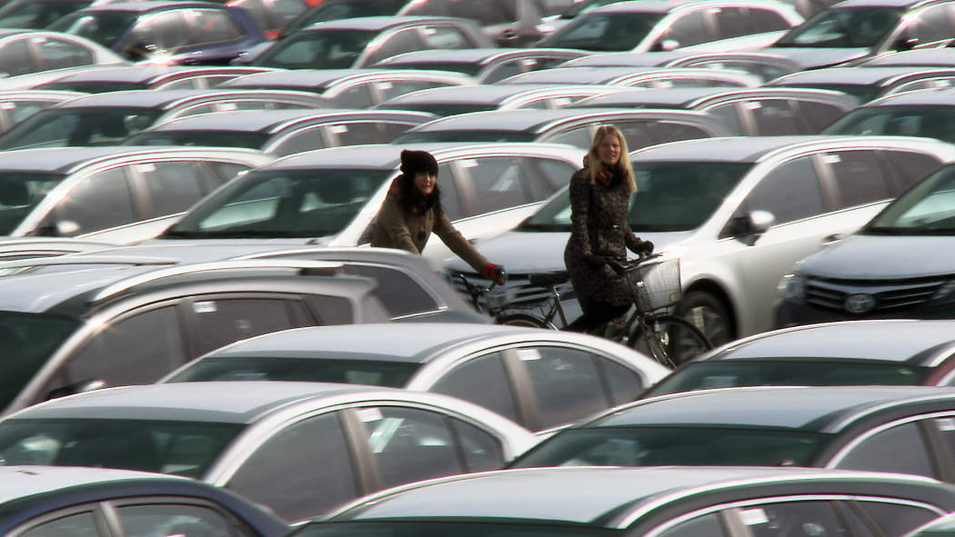 Two cyclists amongst many cars.